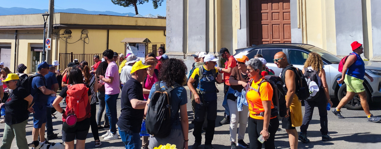 Escursione Sensoriale Gruppo di escursionisti riuniti davanti a una chiesa, con zaini e cappelli colorati